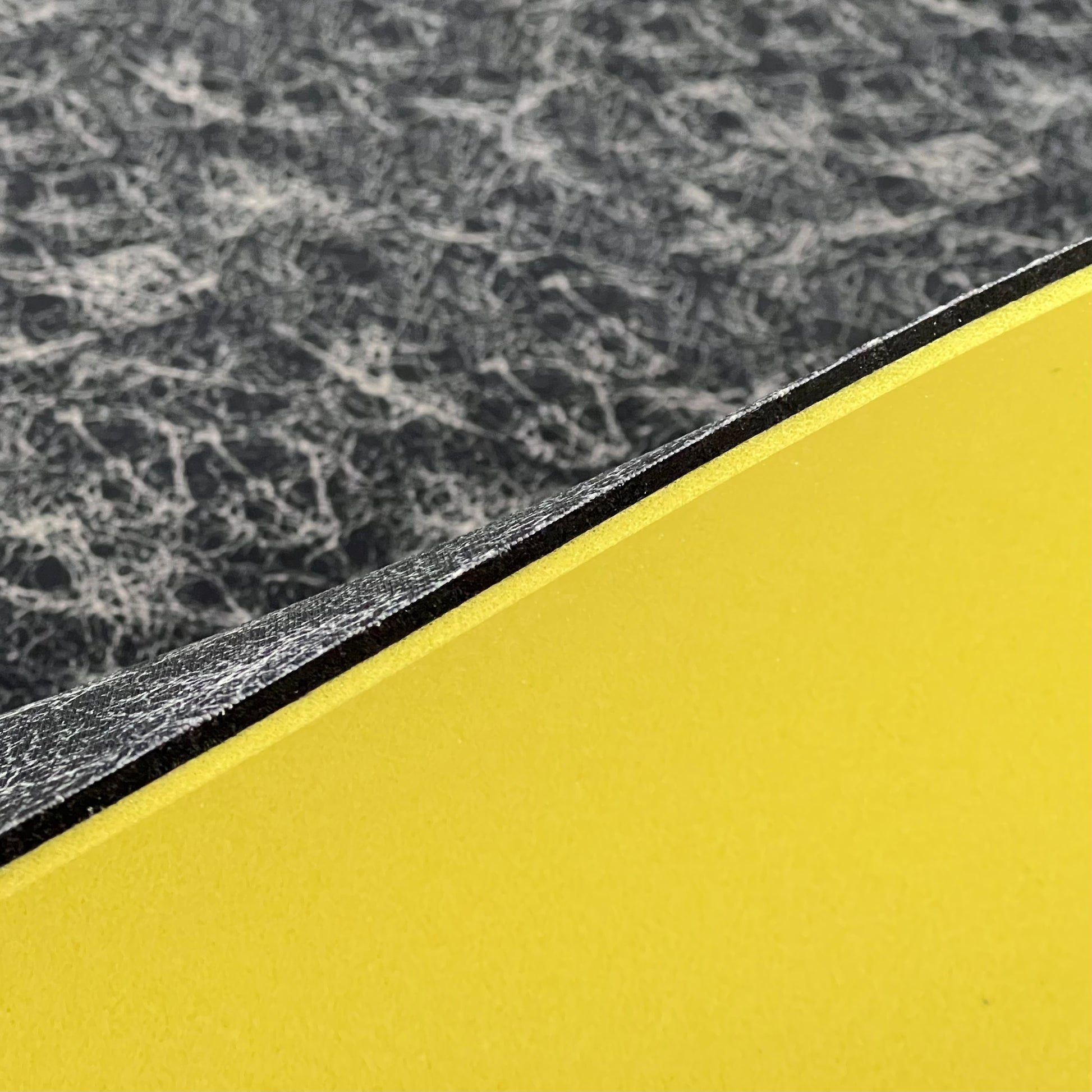 Close up image of side profile of a 1/4" sheet that has 3 layers, the black thin footbed layer, the 1/8"FoamFuzion Layer and the 1/8" VeloShox Layer.