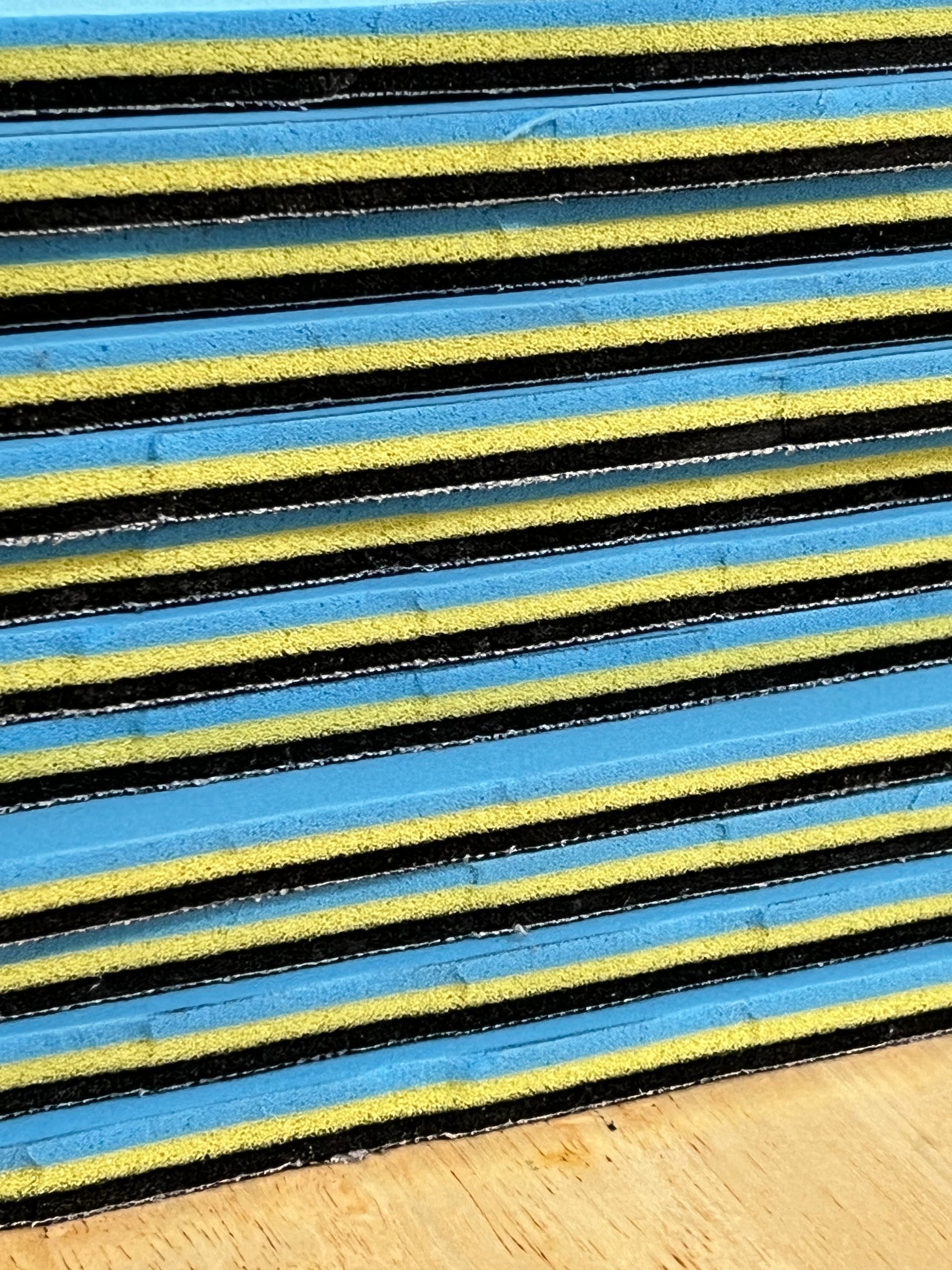 Close-up of textured edge of our 3/8" insole sheet which combines 3 different insole materials plus the Pure silver infused AG 2.0 topliner.
This photo is of a stack 12 of our 3/8" insole sheets from the side profile.
Each sheet's composition is 1/8" Black Foam Fusion foam on top, then the 1/8" VeloShox foam in the middle with the 1.8" BounceBlu foam at the bottom.