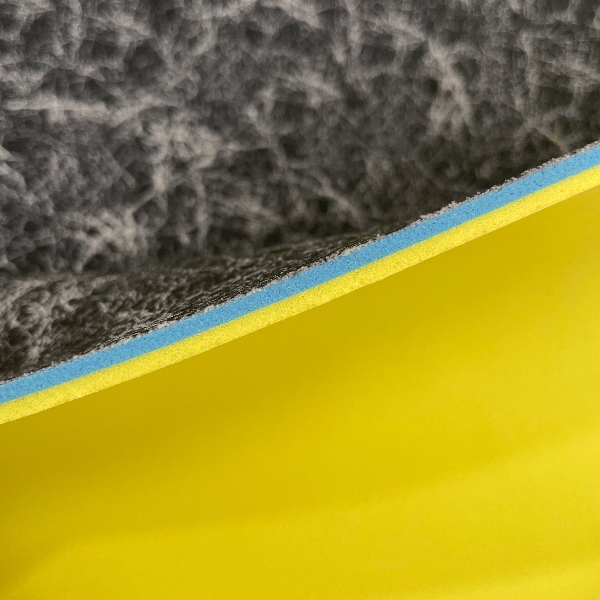 Close up image of side profile of a 1/4" sheet that has 3 layers, the black thin footbed layer, the 1/8"BounceBlu Layer and the 1/8" VeloShox Layer.